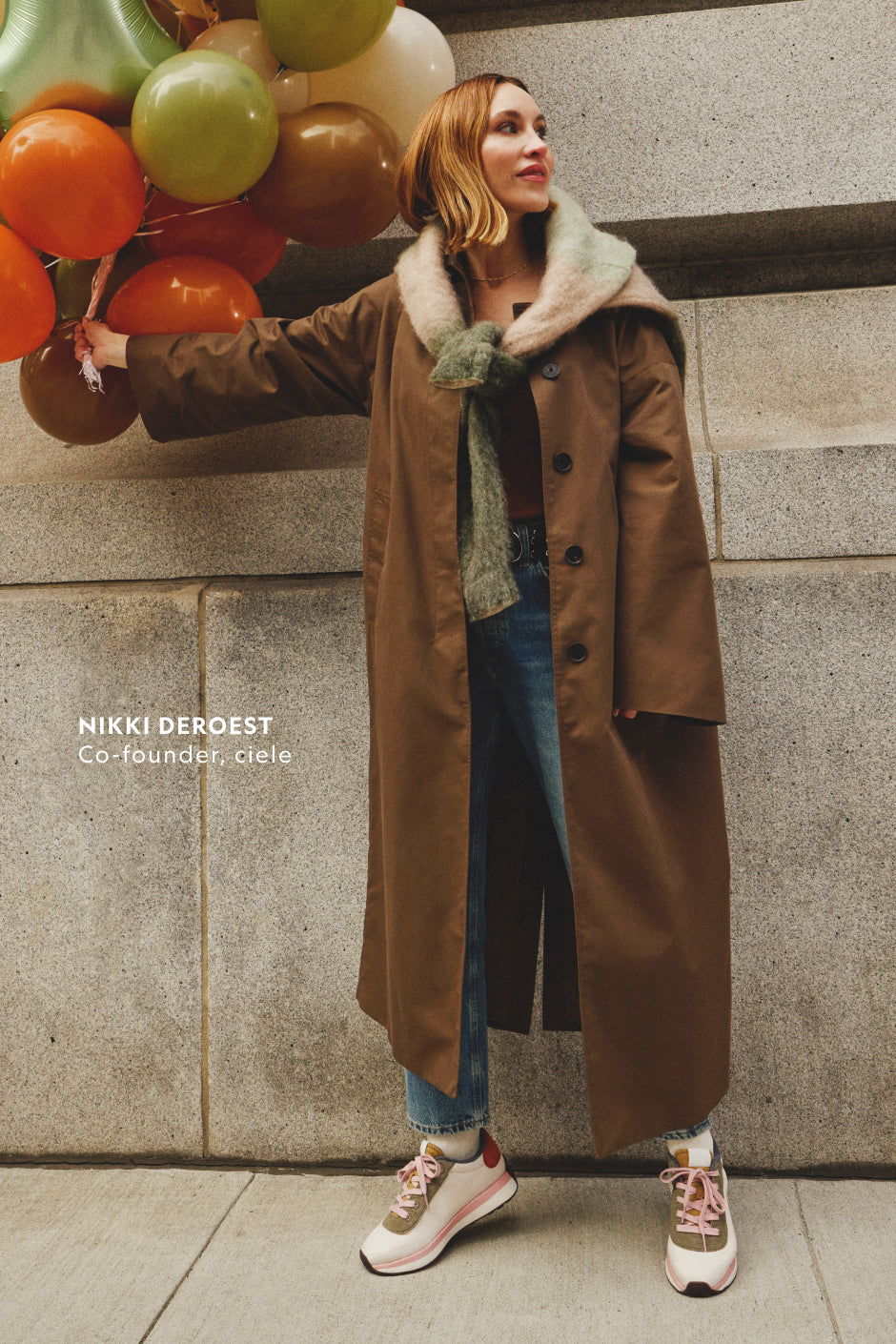 Nikki DeRoest, co-founder of Ciele, wearing a long brown coat and jeans styled with pink Allbirds Varsity sneakers.
